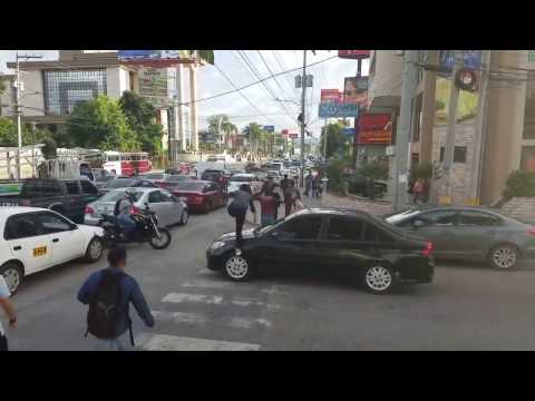 Pedestrians walk over a front car hood that stop in the pedestrian lane